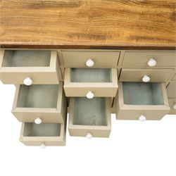 20th century haberdashery style chest, solid elm top over twenty-four assorted drawers with white ceramic knob handles, painted sage green carcass, raised on castors