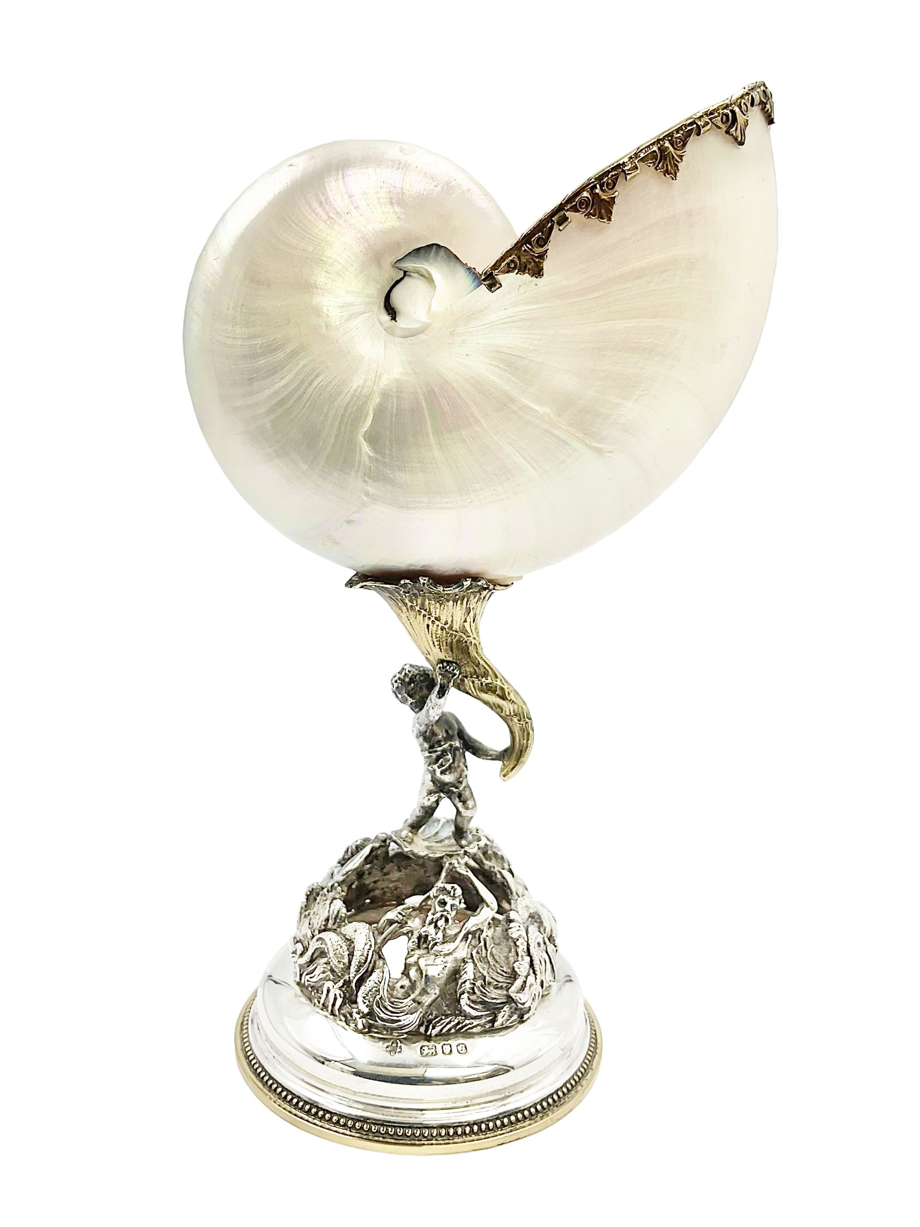 Modern limited edition silver mounted nautilus shell cup, no. 42/150, the pearlescent shell cup with silver-gilt strapwork to rim, upon a stem modelled as a putto supporting a gilt cornucopia and circular domed foot depicting Poseidon amongst swirling waves, hallmarked by St James House Company, London 1980,  H17.5cm