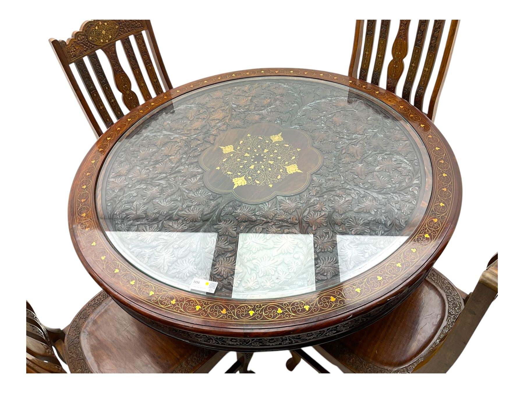 Pakistan carved hardwood brass inlaid circular dining table, and four rail back chairs with saddle seats