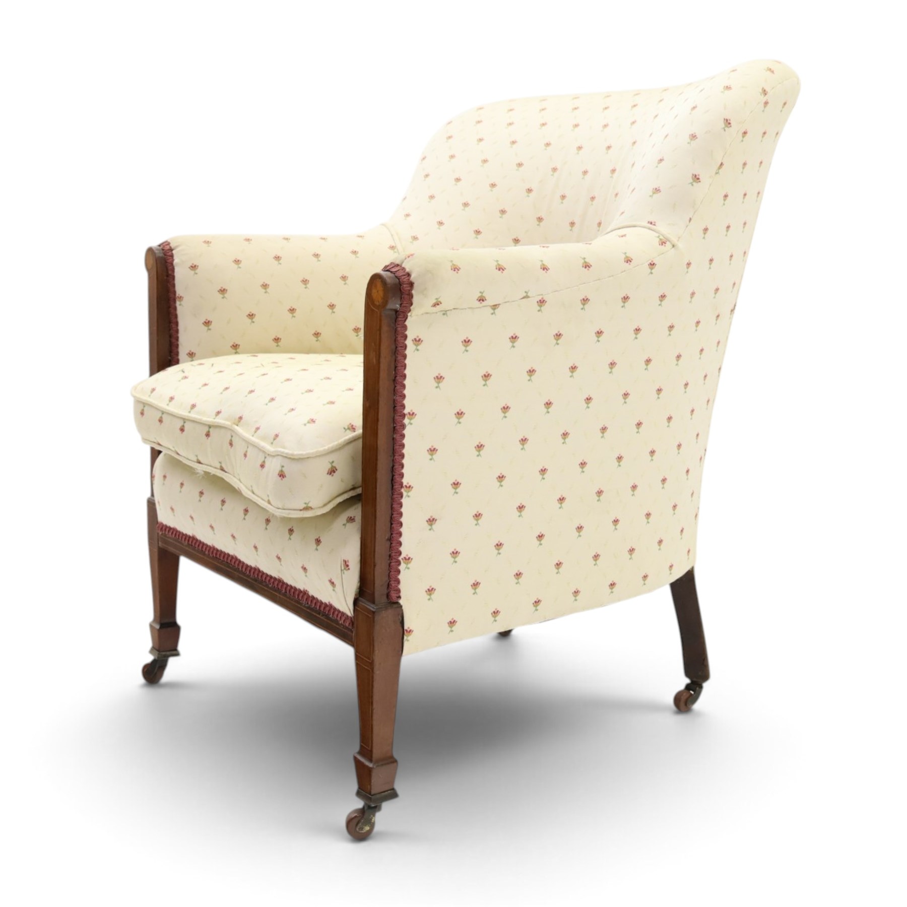 Edwardian inlaid mahogany armchair of modest proportions, spoonback and loose seat cushion on sprung seat upholstered in ivory ground floral fabric, on square tapering supports with ceramic castors