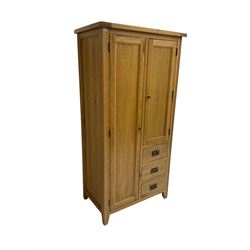 Solid light oak combination wardrobe, fitted with one cupboard enclosing hanging rail, the shorter cupboard above three drawers, on tapered feet