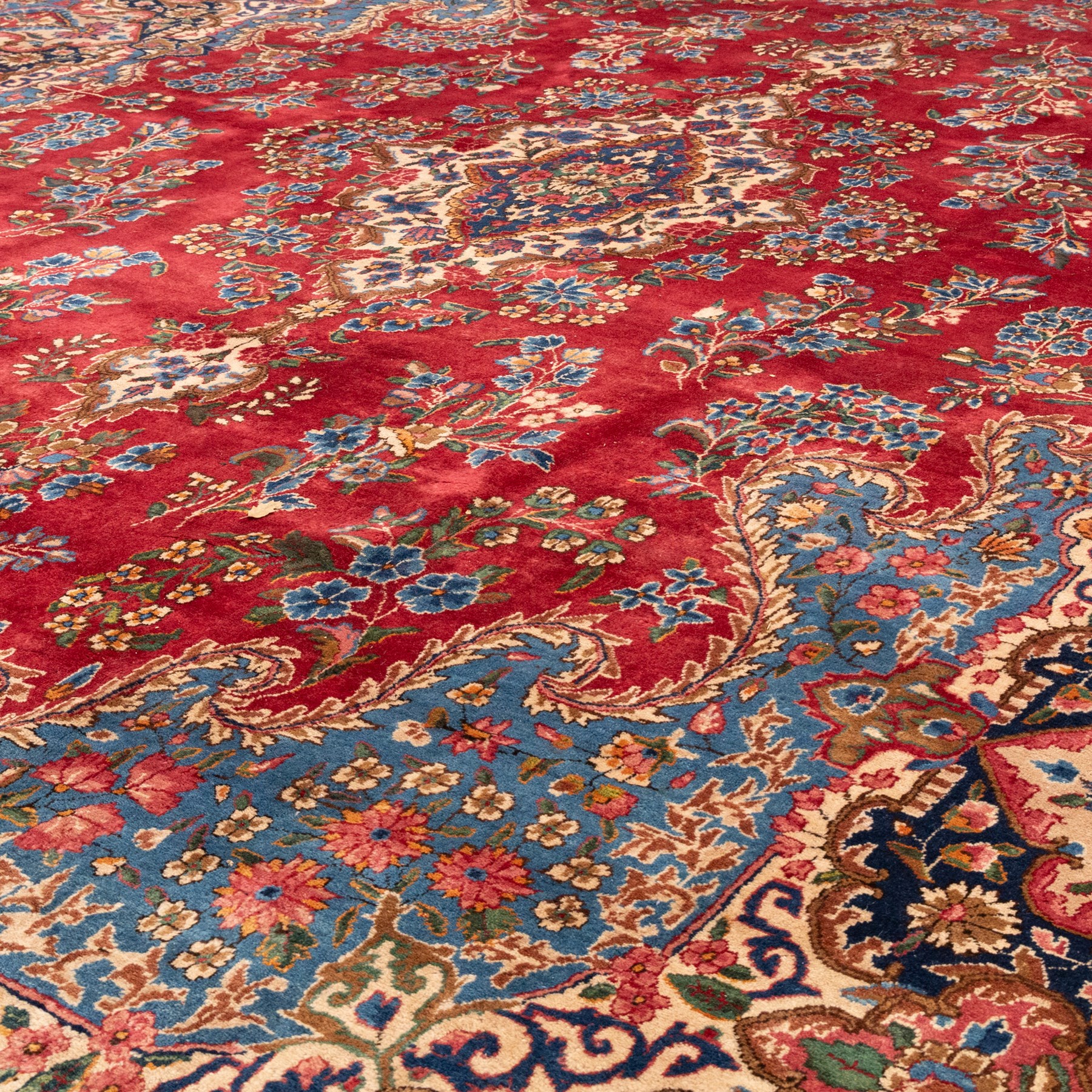 Fine Persian crimson ground Kashan carpet, the busy field with a central floral pole medallion surrounded by bouquets of flowerheads and trailing foliage, the shaped cyan spandrels similarly woven, enclosed by a wide foliate guard band of stylised palmettes and floral designs