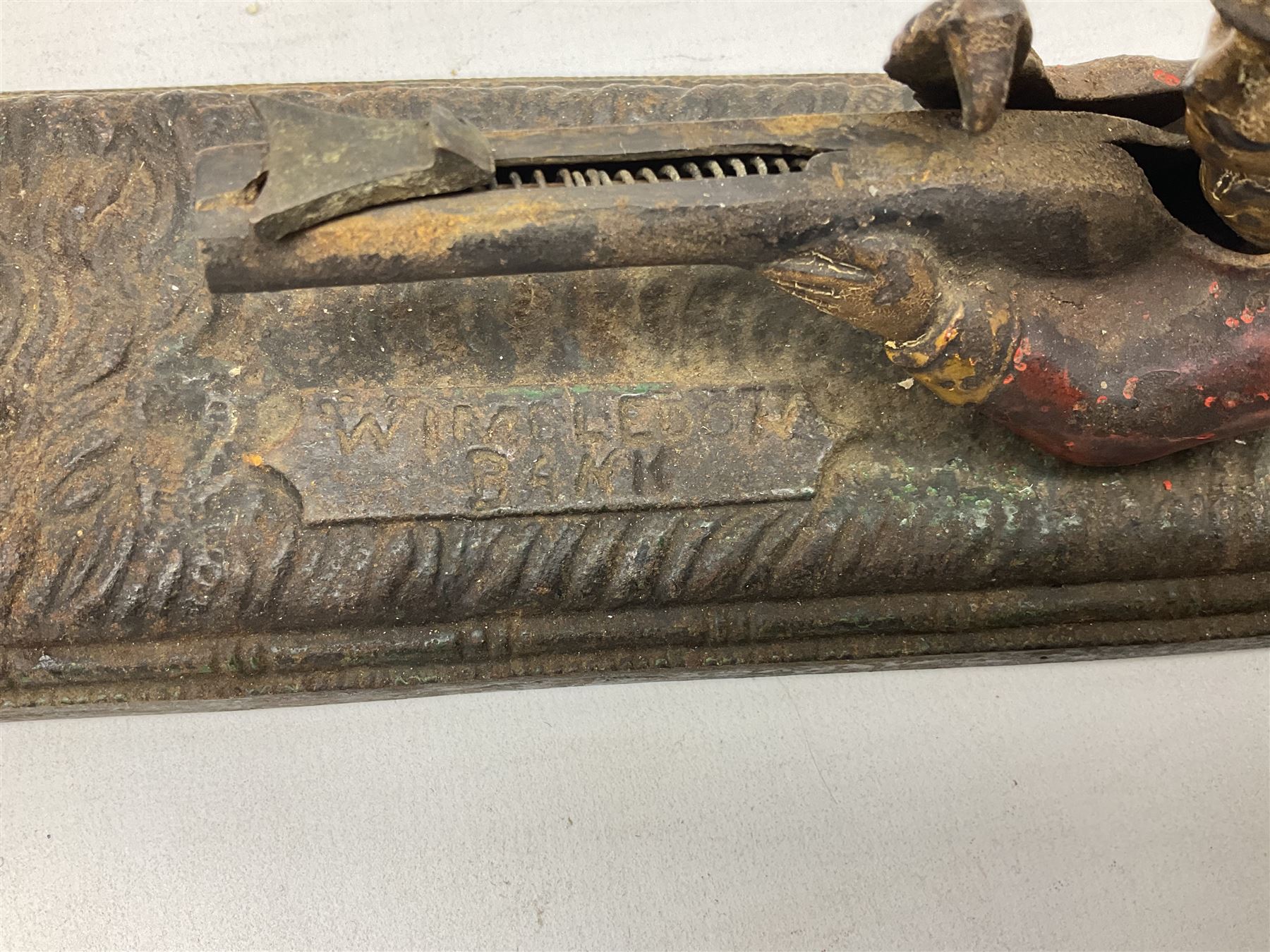 Very rare 19th century John Harper & Co. mechanical cast-iron money box, registered number 33821 patented 1885, inscribed on metal plaque 'Wimbledon Bank', based on the Queen's Trophy for shooting at Wimbledon, depicting a British Infantry man in red tunic and blue trousers lying on the ground using a gun to fire a brass coin launcher into a pill box with fixed flag above L30cm