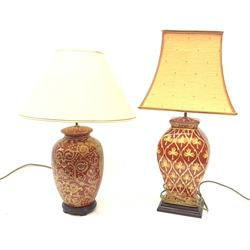 A table lamp of ovoid form, the red ground with gilt foliate decoration, with shade, lamp H45cm, together with a similarly decorated table lamp, with shade, H48.5cm. 