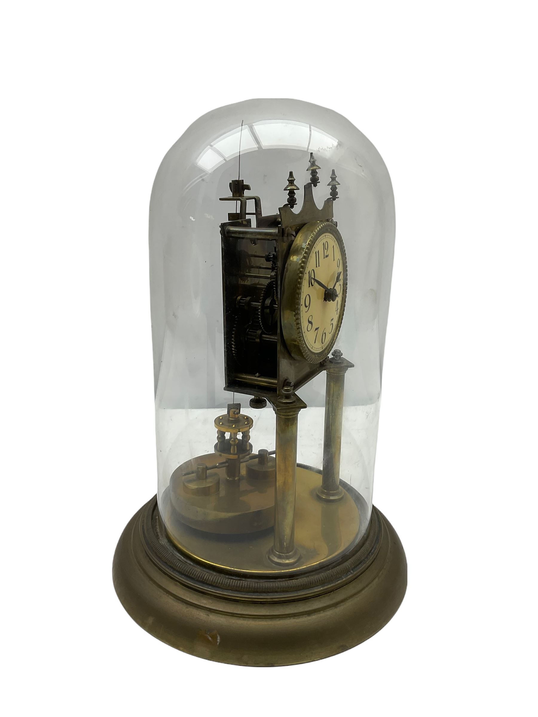 An anonymous early 20th century German 400-day torsion clock, with a circular enamel dial, upright Arabic numerals and minute track, spade hands under a glass shade, circular rotating pendulum with regulation, on a circular brass base with adjustable feet. 
H33cm

