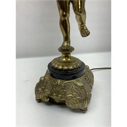Gilt metal table lamp, modelled as a putti holding aloft a cornucopia of flowers, upon a marble effect and ornate gilt metal base, with fabric tassel lamp shade, total H92cm
