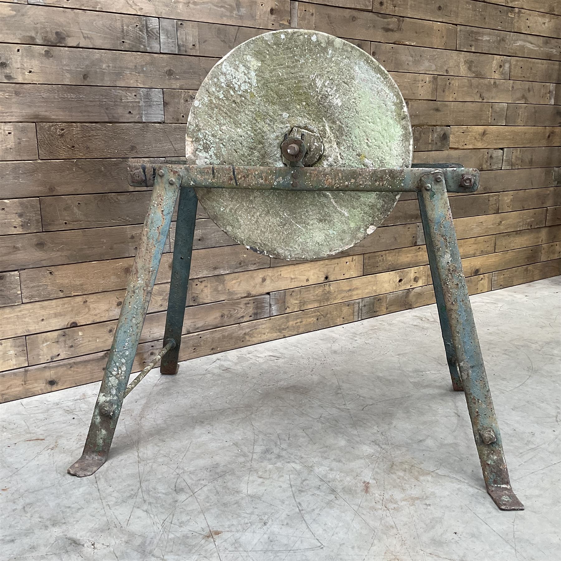 Vintage grindstone sharpening wheel mounted on metal stand, and a cast iron water pump