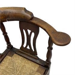 18th century country elm and oak corner chair, the shaped cresting rail terminating to swept arm resets, supported by turned columns and pierced shaped splats, over a drop-in rush seat, raised on square supports united by box stretcher