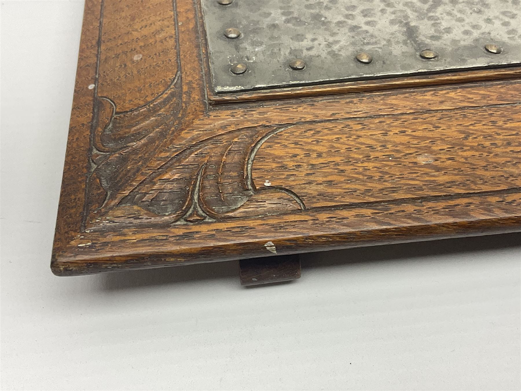 Arts and Crafts oak stand by Arthur Simpson of Kendal, of rectangular form with central hammered pewter panel, surrounded by a border with carved foliate corners, upon two bar supports, bearing label detailed 