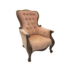Victorian walnut framed armchair, shaped back with carved and scrolled arm terminals, upholstered in buttoned pale pink fabric, raised on cabriole supports terminating in castors