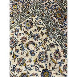 Persian Kashan Ivory ground carpet, the busy field decorated all over palmettes and trailing branches, scrolling border interspersed with stylised plant motifs, within guard stripes