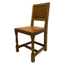 Eagleman - pair oak dining chairs, figured burr panelled backs over tan leather upholstered seats with stud band, the seat rail carved with eagle signature, on octagonal front supports joined by plain stretchers, by Albert Jeffray of Sessay, Thirsk