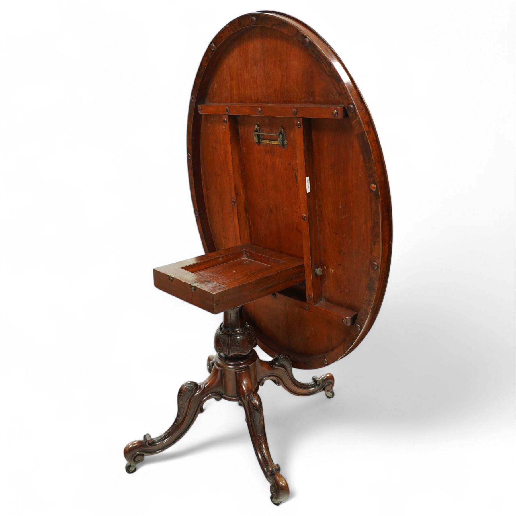 Victorian 19th century burr walnut oval centre table, hinged top above a carved pedestal supported on a scrolled carved quadruped base