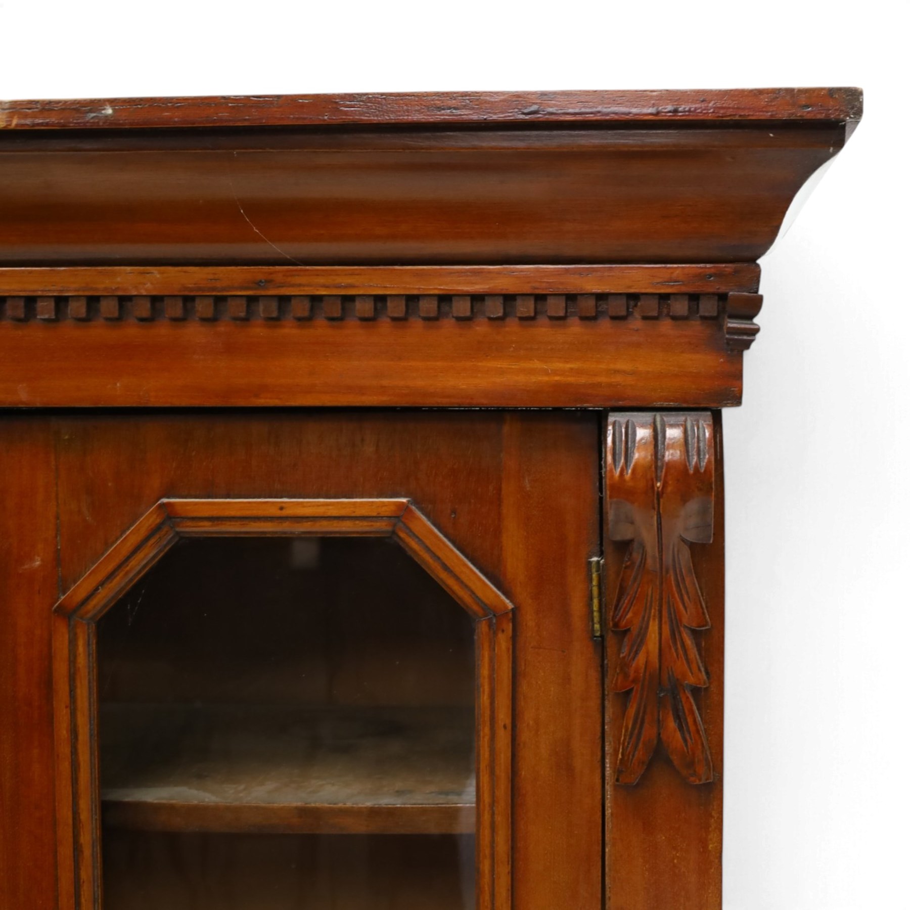 Victorian mahogany bookcase on cupboard of slender proportions, projecting cornice over dentil-frieze, fitted with twin-glazed doors enclosing three shelves, flanked by acanthus corbels, the base fitted with single frieze drawer over panelled cupboard, on skirted base