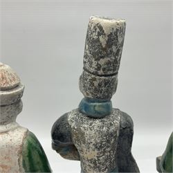 Three Chinese terracotta court attendant tomb figures, probably Ming Dynasty, two examples decorated in Sancai green glaze, the third example decorated in two tone blue glaze, each upon stepped square bases, tallest H22.7cm