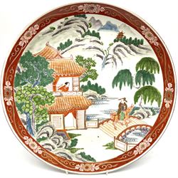 Large 20th century Chinese plate, decorated in polychrome enamels with a figure on horseback traversing a bridge, and figure at the window of a pagoda, within a mountainous landscape, the whole contained within a red border decorated with scrolling foliate motifs, D37cm