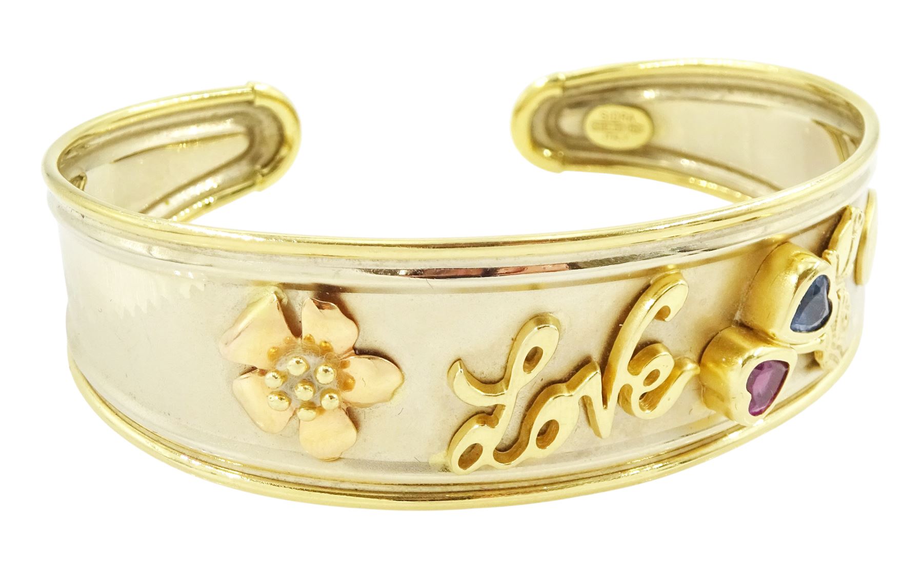 18ct gold 'Love' torque bangle, set with a heart cut pink sapphire and blue topaz, stamped Sidra 750