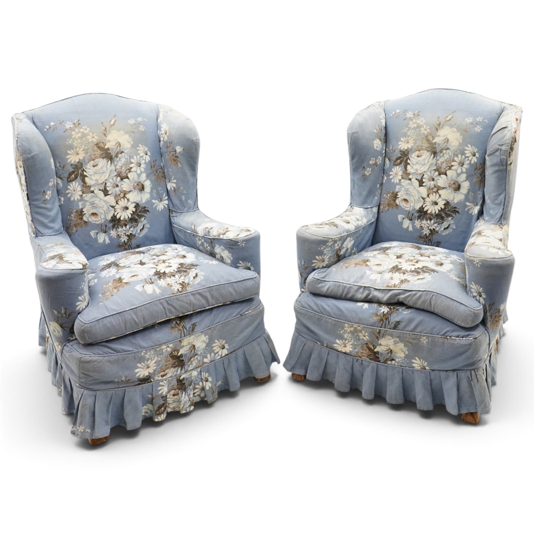 Pair of Queen Anne wingback armchairs, high back over out-swept arms, raised on ball-and-claw feet, upholstered in sky-blue ground floral chintz loose upholstery with pleated skirt and squab cushion