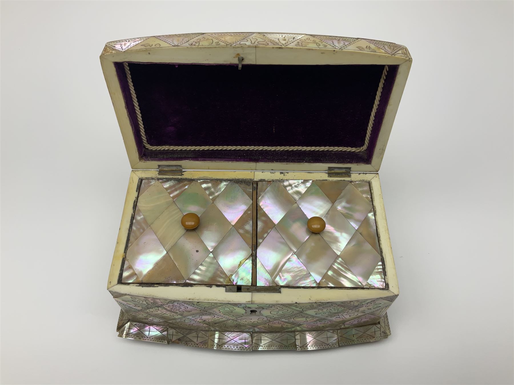Victorian mother of pearl tea caddy, of rectangular bow-fronted form, the body with floral, bird and geometric engraved mother of pearl panels, white metal shield plaque to the cover inscribed with the initials G.J.A and similar escutcheon, the two division interior with ivory edging and two panelled mother of pearl lids, on four vegetable ivory bun feet L20cm, together with a similar style mother of pearl card case (2) This item has been registered for sale under Section 10 of the APHA Ivory Act