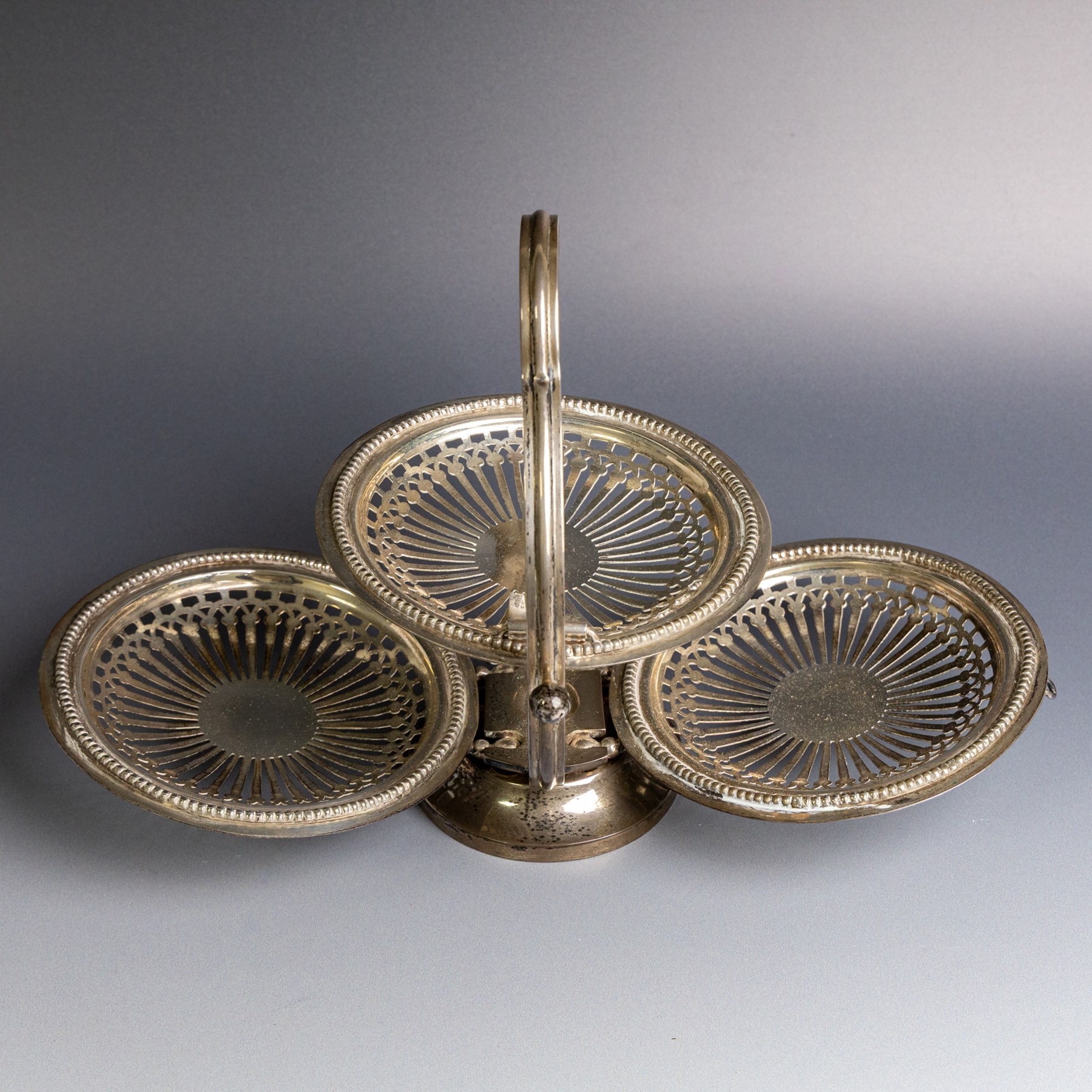 Indian silver folding cake stand, of circular form with pierced decoration, loop handle and circular foot, when folded H18cm