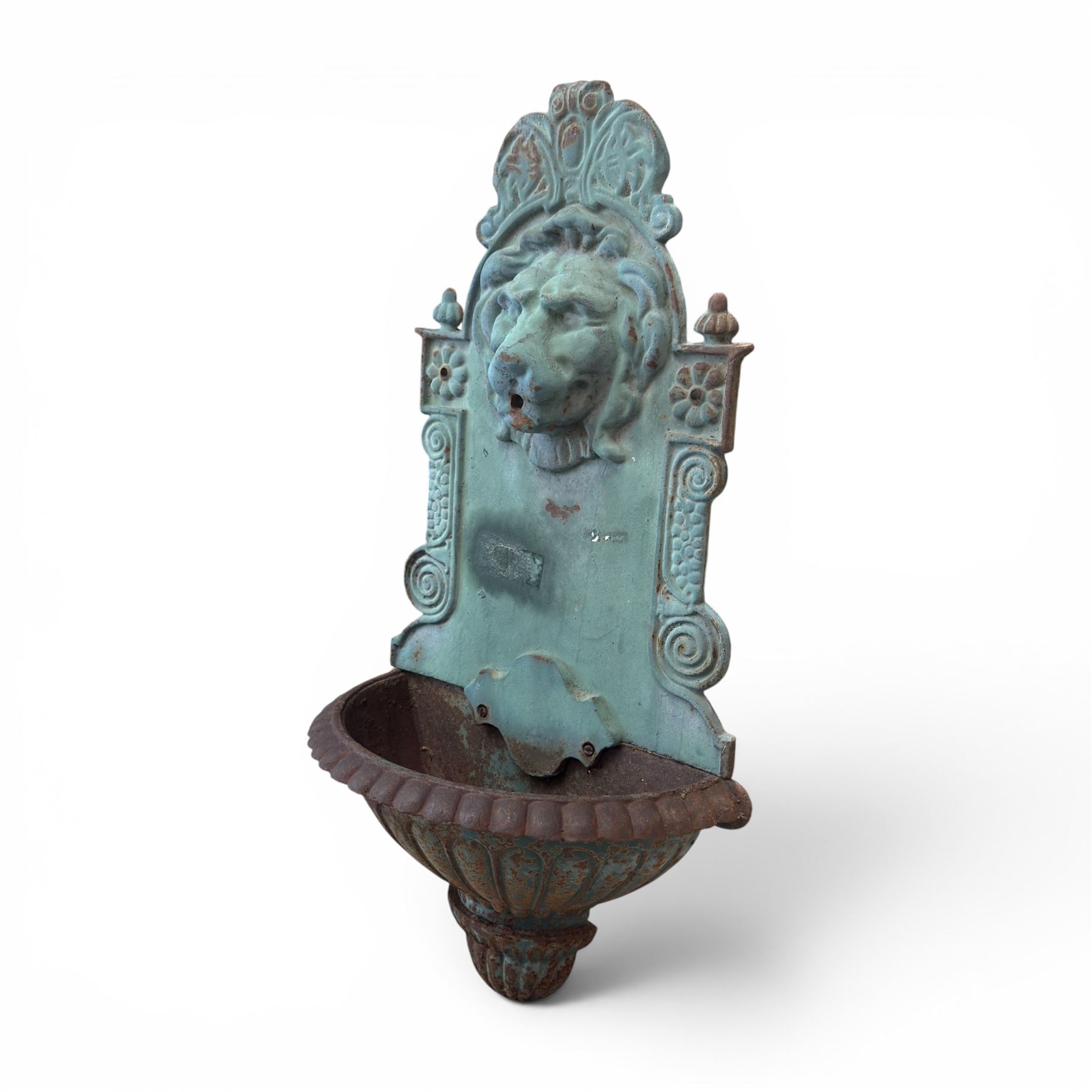 Antique cast iron wall fountain, cartouche cresting rail over a lion mask spout, with scroll and floral decoration over a scalloped basin, in rustic turquoise painted finish with rusted patina