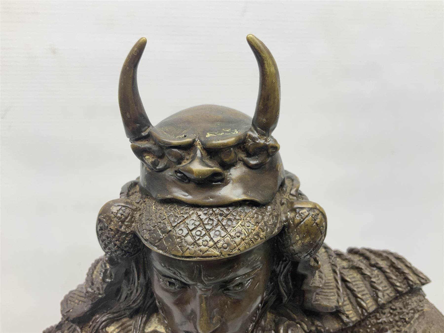 Bronze figure of a samurai standing wearing armour and holding a naginata, upon a rocky base, H48cm