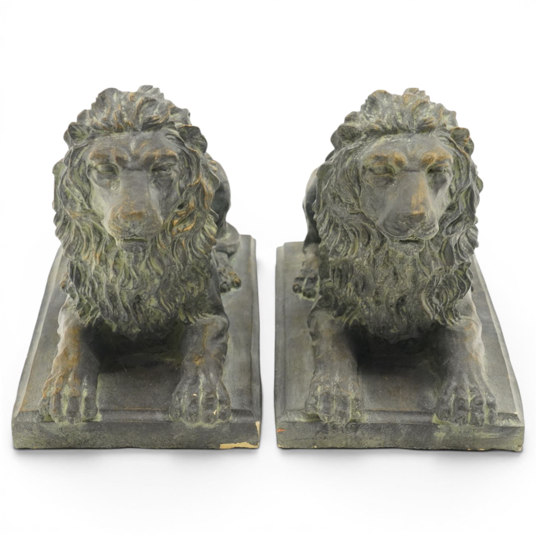 Pair of bronze-effect composition stone recumbent lions, with verdigris-style weathered finish, each raised on rectangular plinth base