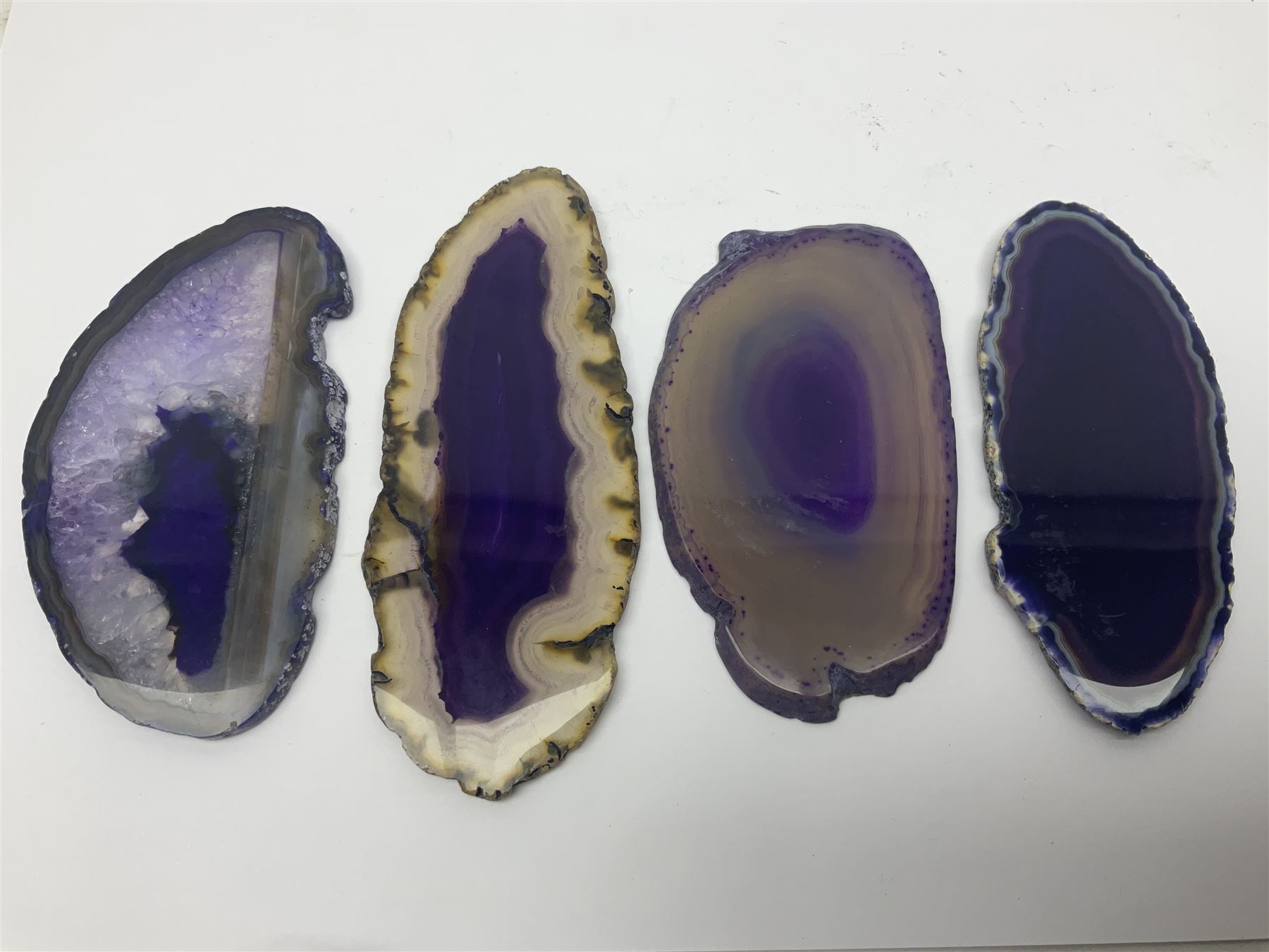 Four purple agate slices of various sizes, polished with rough edges