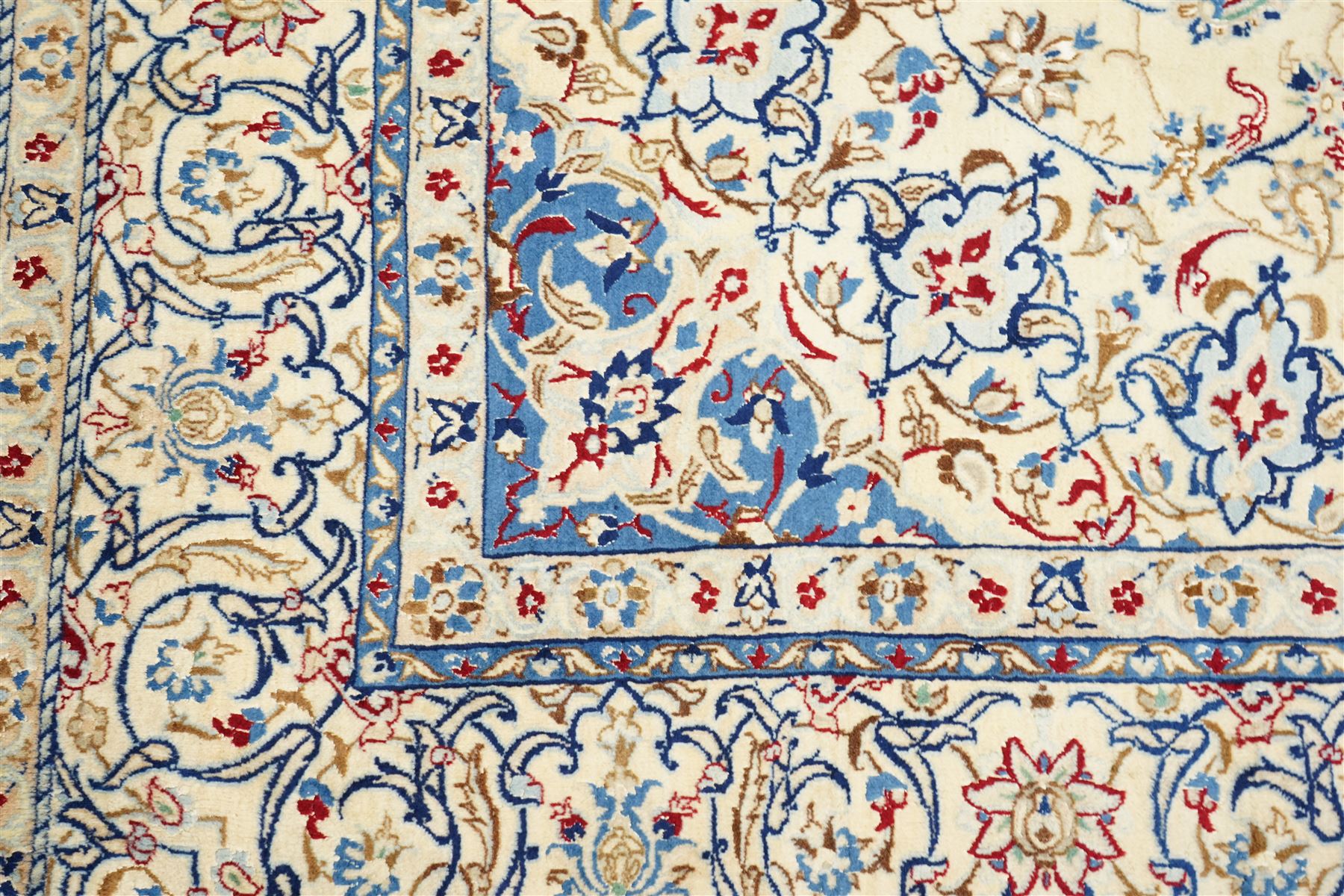 Central Persian Nain hand-knotted carpet, ivory field with central finely drawn cusped medallion of radiating palmette and arabesque form with scrolling vine work, flowering tendrils and stylized foliate motifs in a palette of pale blue, indigo, crimson and sage accents, spandrels of conforming design enclosing intricate floral sprays and arabesques within  multiple borders and narrow guard stripes, with cotton fringe ends 