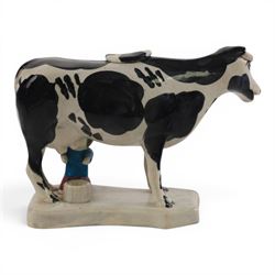Three Staffordshire cow creamers, one with treacle glaze, the other two painted black and white with a seated figure of a milkmaid, H14cm