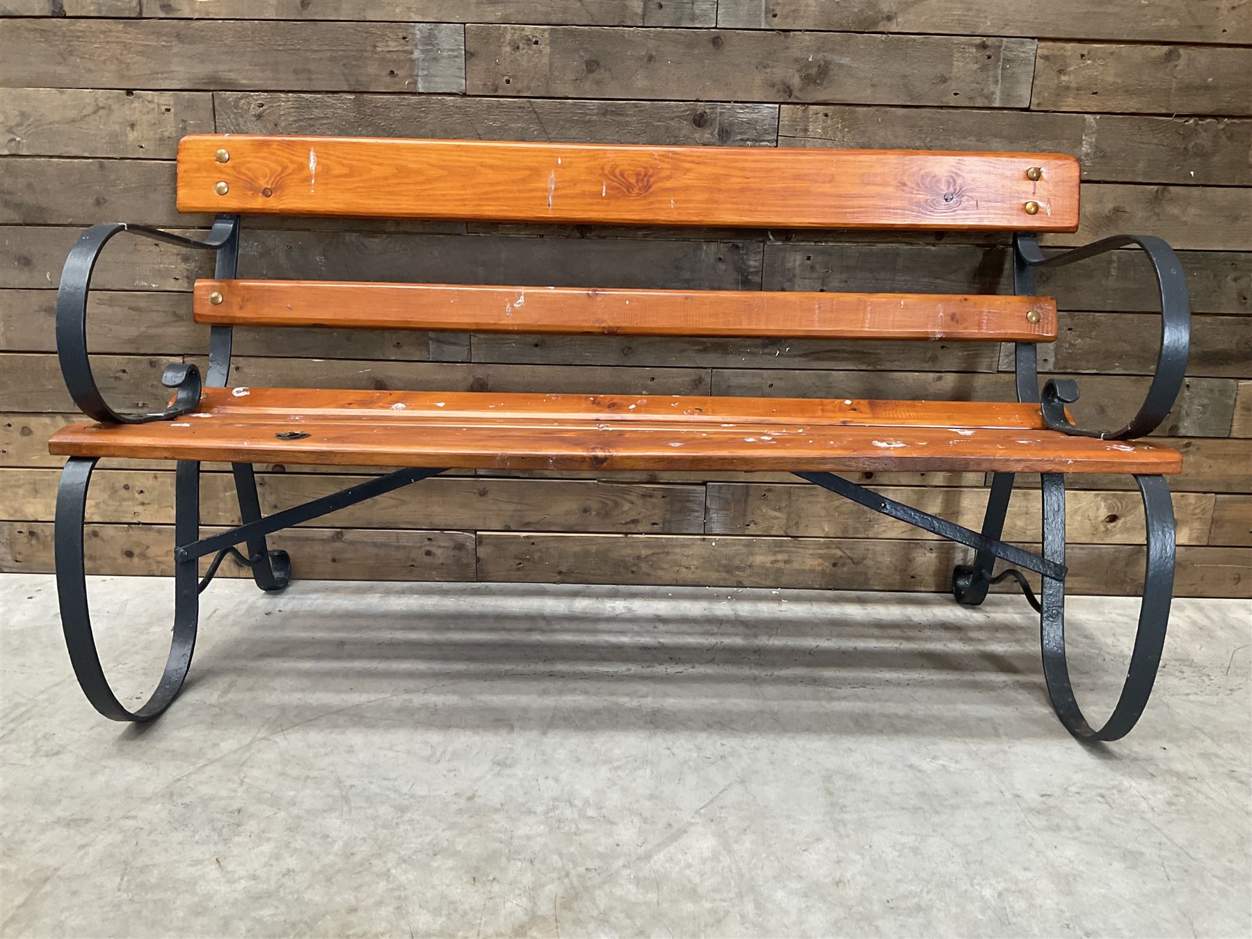 Wrought metal scrollwork and wood slatted garden bench