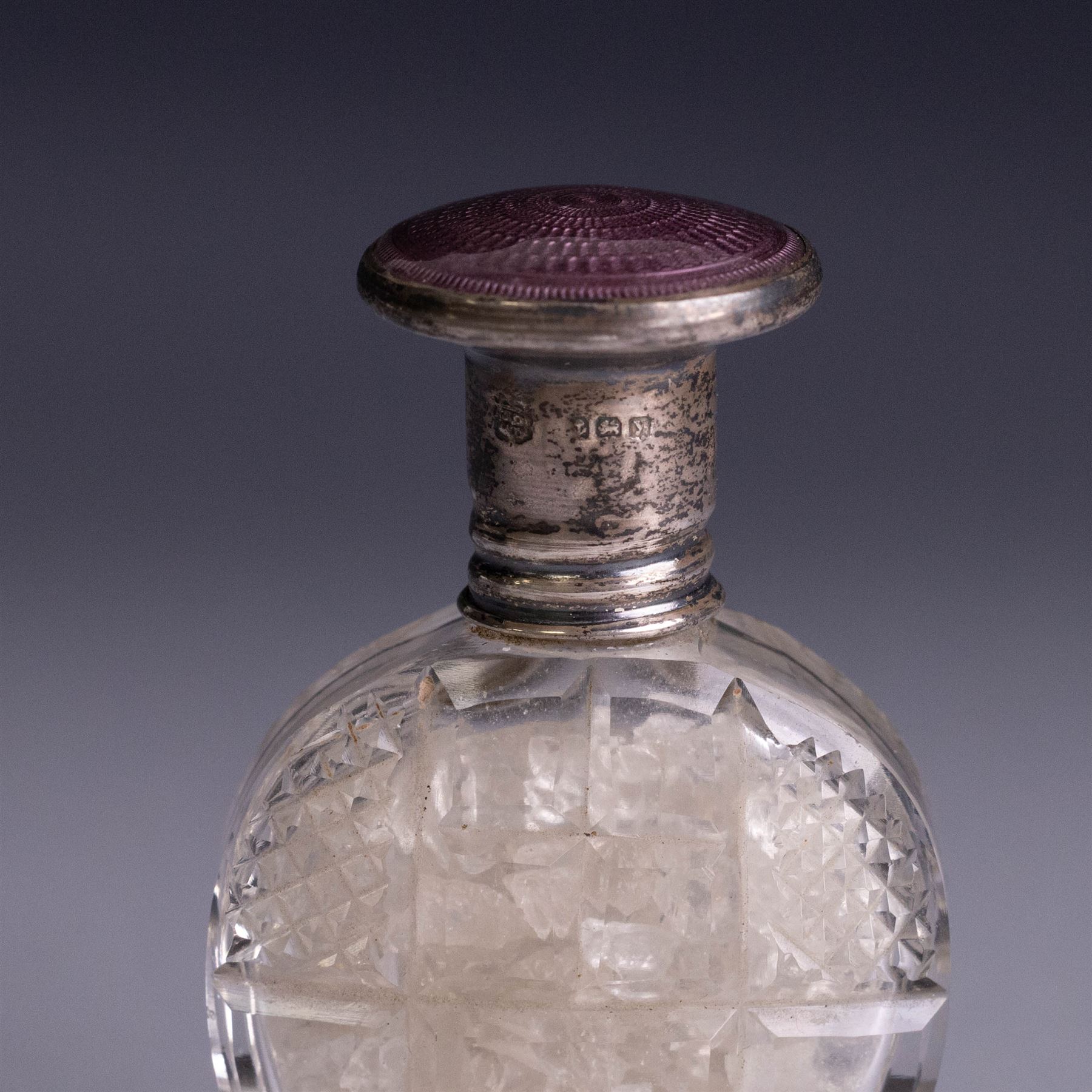 Three silver topped scent bottles, comprising cut glass example with pink guilloche enamel cover, oval example with blue guilloche enamel cover and one other, all hallmarked, largest H6.5cm