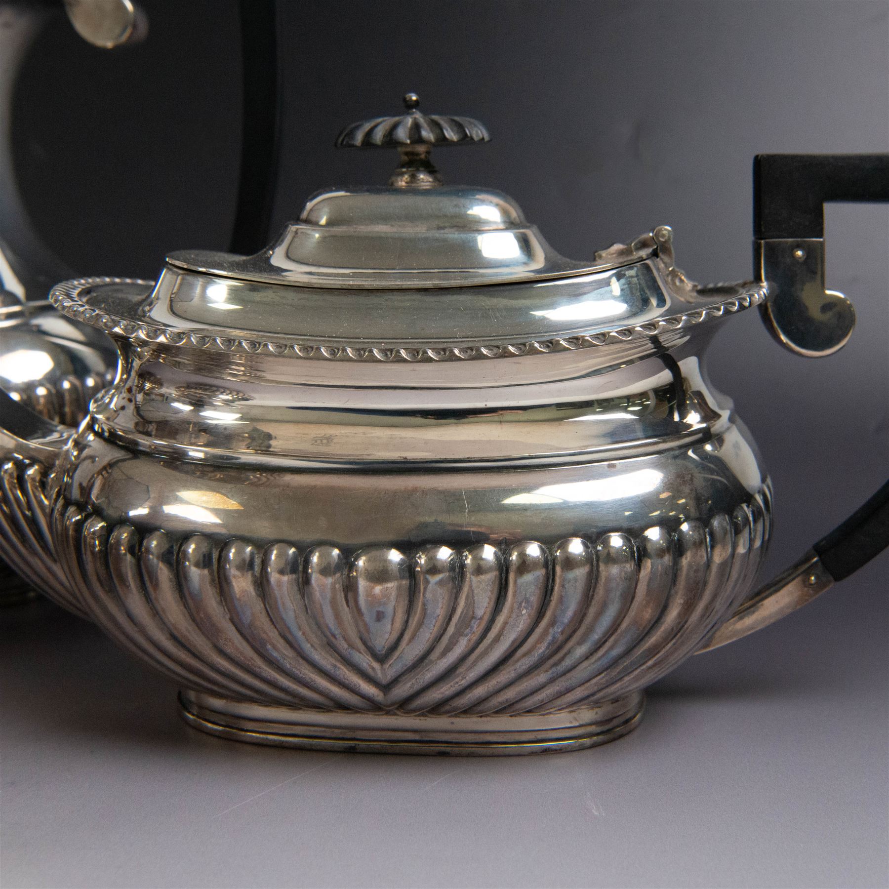 Edwardian silver four piece tea service, comprising coffee pot, teapot, twin handled open sucrier and milk jug, all of oval bellied form, part fluted and with oblique gadrooned rim, with Bakelite type handles and finials to teapot and coffee pot, hallmarked Fordham & Faulkner, Sheffield 1913