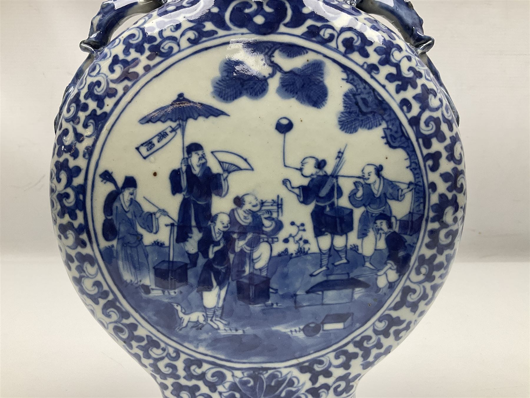 19th century Chinese blue and white moon flask vase, the central panel depicting musicians, bordered by floral, foliate and scroll decoration, with lizard handles to each shoulder, upon an oval foot, H31cm 