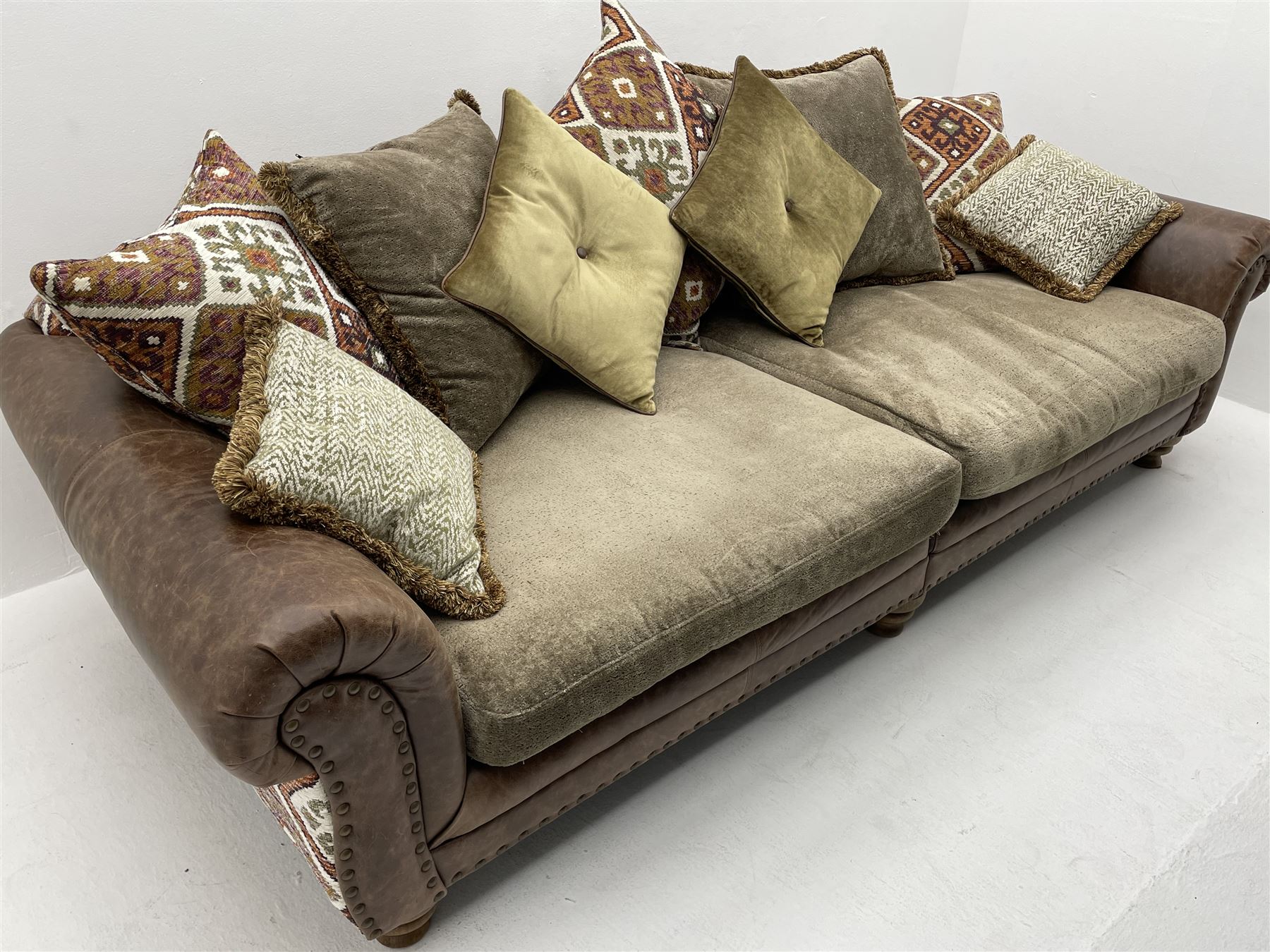 Alexander James - Grand two sectional sofa upholstered in studded leather and fabric, with contrasting kilim patterned scatter cushions, scrolling arms and turned front supports 