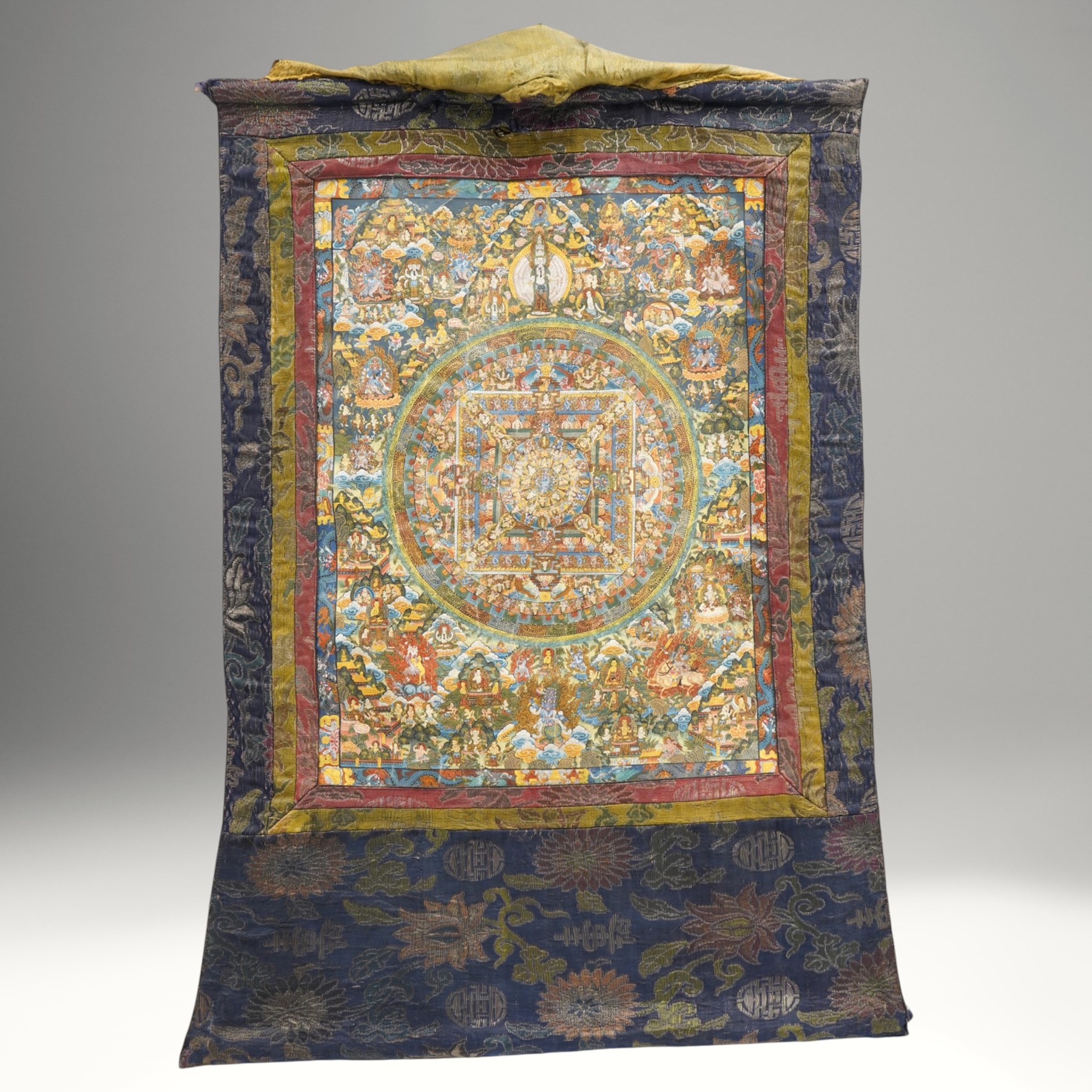 Two 19th century Tibetan Thangkas, depicting Bhavachakra or the Wheel of Life, and the other depicting a Buddhist mandala, each mounted on brocaded fabric, image sizes 64cm x 46cm and 62cm x 47cm (2)