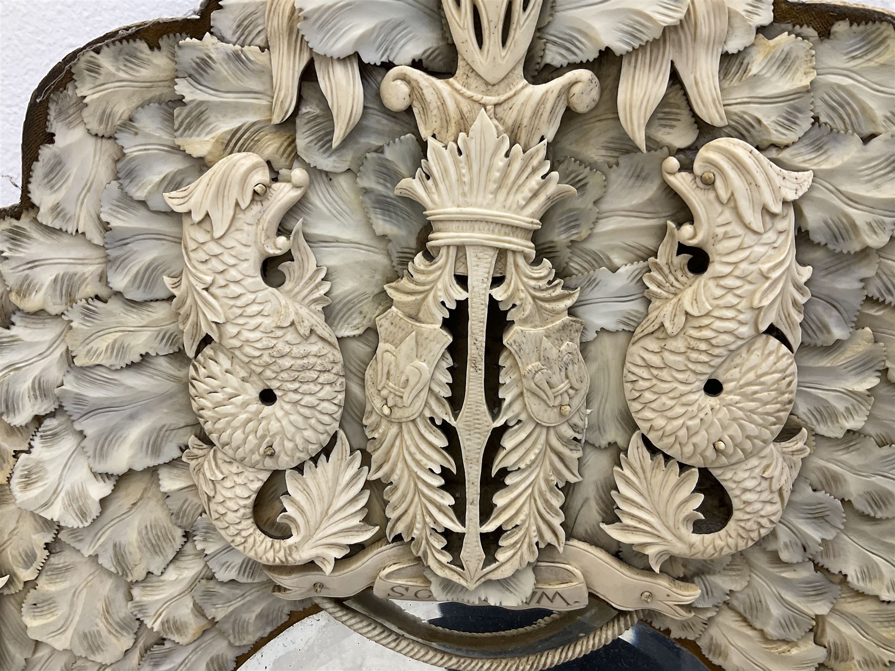 Pair 19th century French Dieppe bone and ivory wall mirrors, the oval bevelled mirror plates within rectangular frames with shaped tops, profusely decorated with ivory leaves, further detailed with carved bone armorial type crest inscribed 'SGOTORVM', putti, fish and mask heads, H81cm W48cm