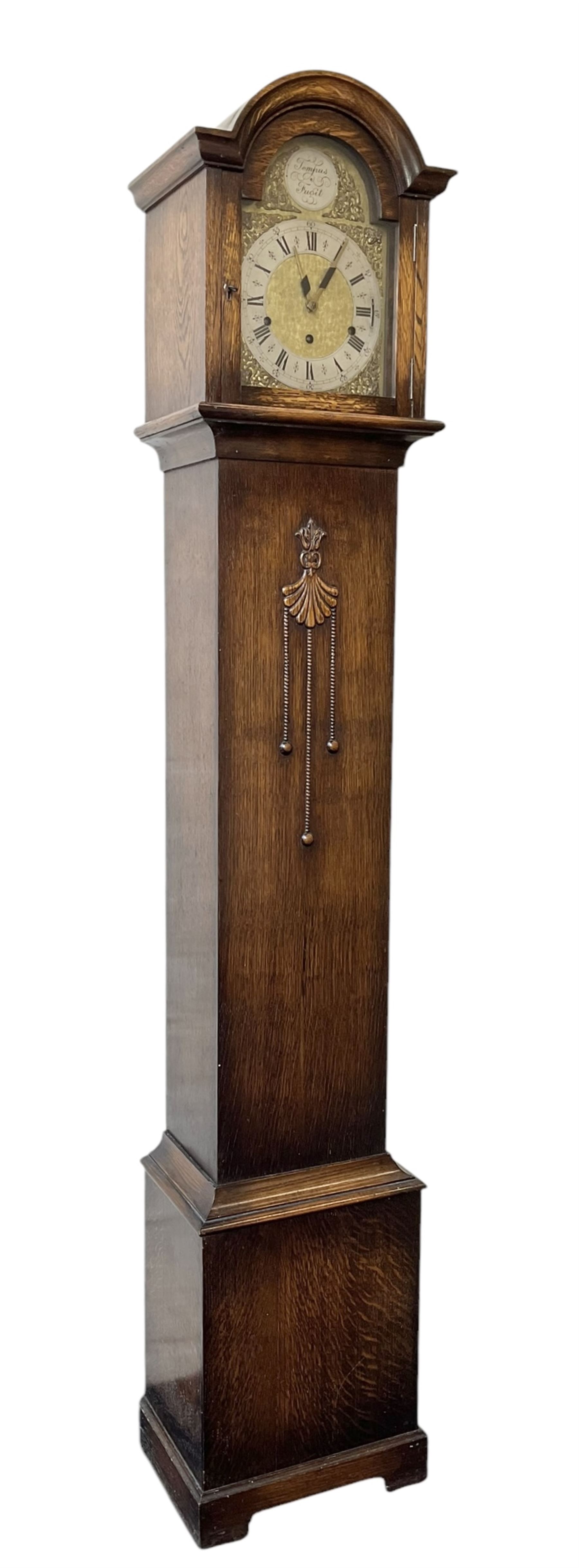 English-1930’s 8-day oak cased grandmother clock, with a break arch hood and trunk with applied carving, brass dial with silvered chapter ring and matted dial centre, three train Westminster chiming movement chiming the quarters and hours on12 gong rods. With pendulum.