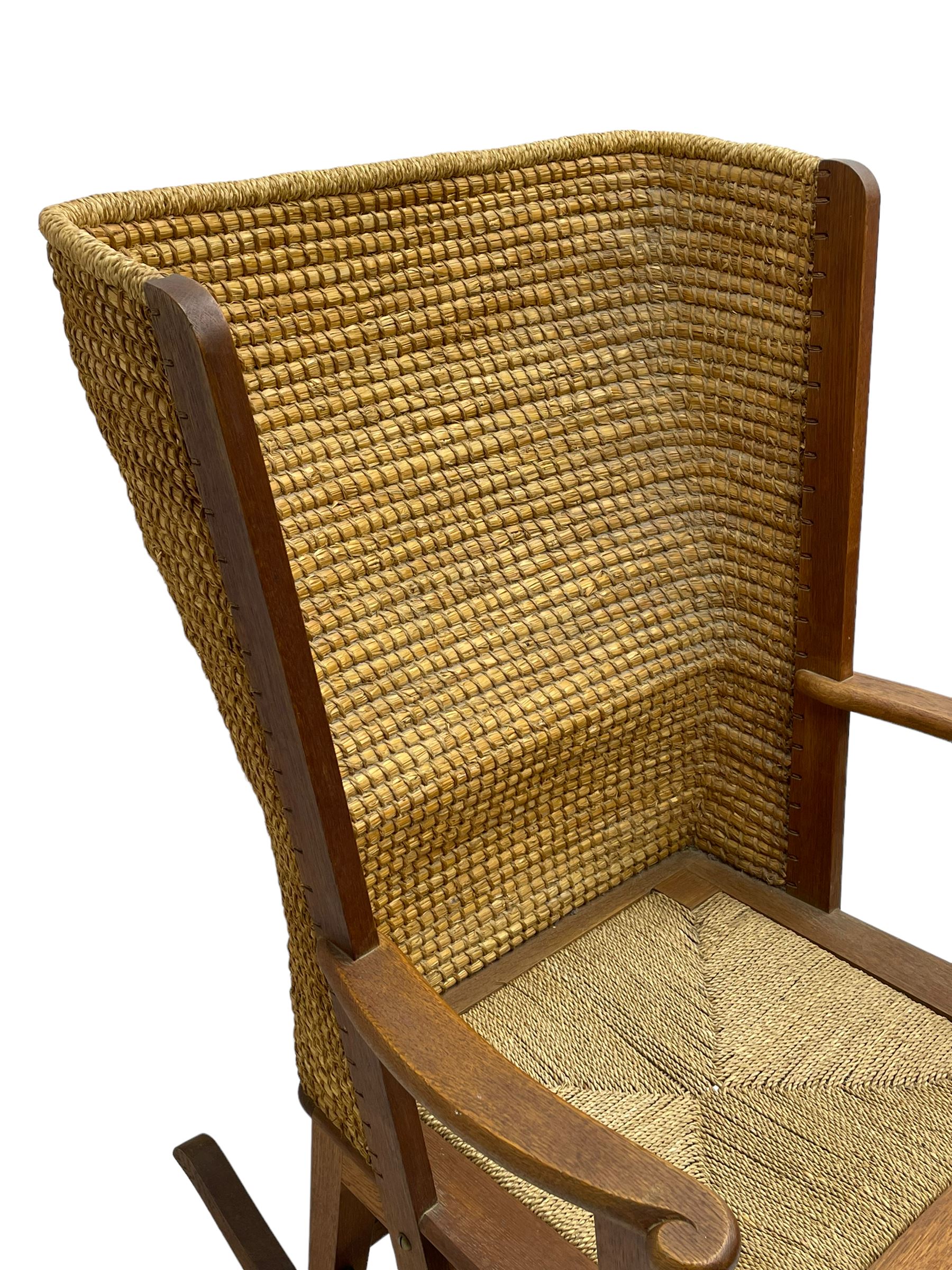 Reynold Eunson (1932–1978) for David Munro Kirkness, Kirkwall, Orkney - oak framed Orkney rocking chair, woven straw curved back, drop-in rush seat, the arm terminals with carved end scroll, on square tapering supports joined by plain stretchers, the front rail inscribed with makers marks