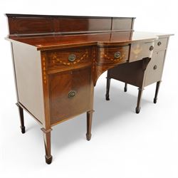 Edwardian Sheraton Revival inlaid plum pudding mahogany serpentine sideboard, rectangular top with raised gallery above bowed frieze drawer finely inlaid with central neoclassical urn motif, flanked by two drawers with swags and ribbon bows, above a cellarette drawer and cupboard, on square tapered supports with spade feet 