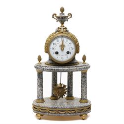 French- early 20th century portico clock garniture, 8-day drum movement decorated with laurel leaves to the glazed bezel and surmounted by a decorative urn with scroll handles, raised by four matching columns on a granite effect oval base with toupee feet, convex enamel dial with gilt pierced hands, Arabic numerals, minute markers and a garland of flowers, twin train Parisian rack striking movement, striking the hours and half hours on a bell. With a sunburst pendulum and key and a matching pair of two-light candelabra.
