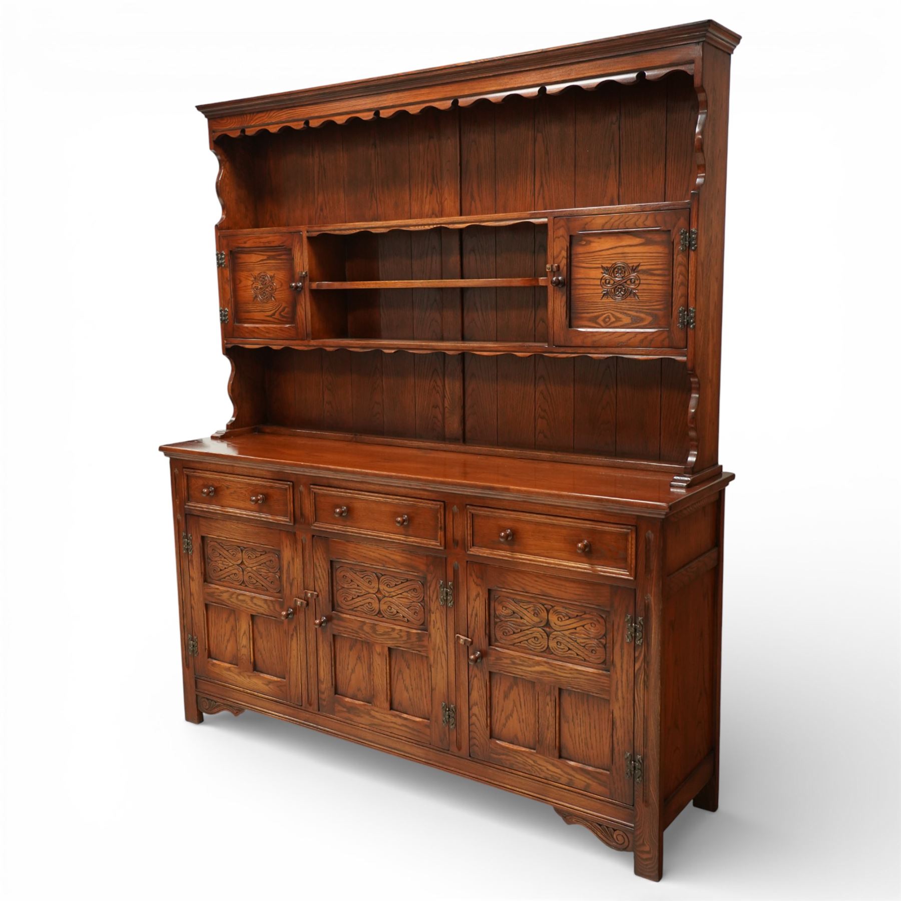 20th century oak dresser, moulded cornice above open plate rack with shaped frieze, flanked by two cupboard doors enclosing shelving, the base fitted with three drawers over three fielded panel cupboard doors, raised on bracket feet