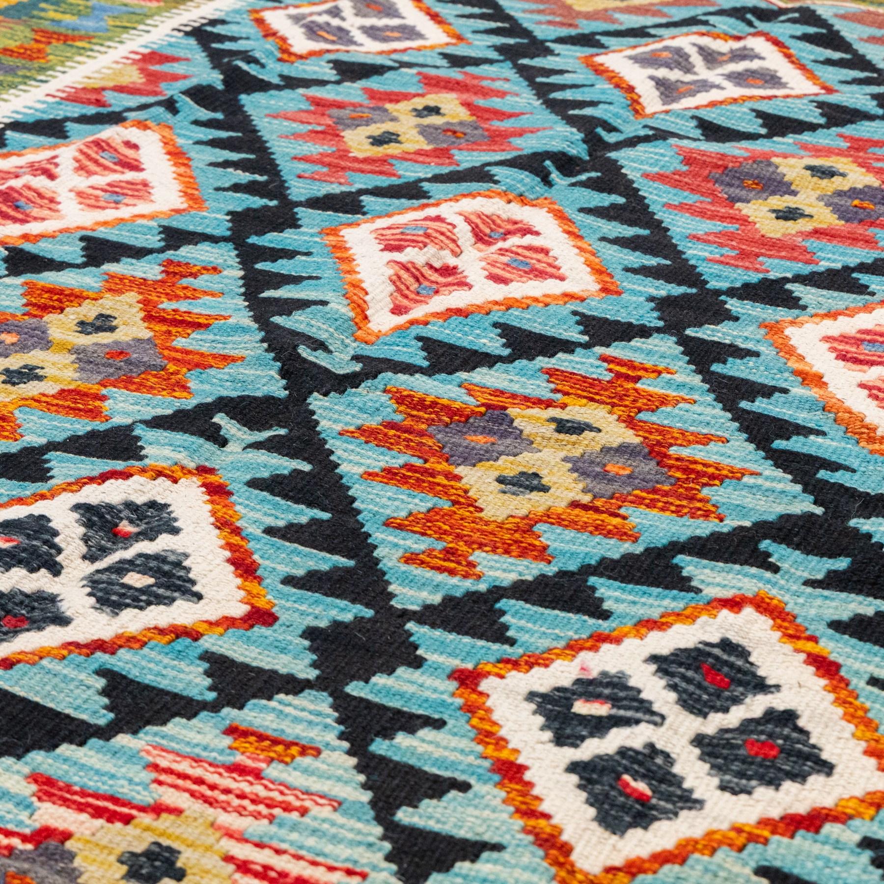 Afghan kilim cyan ground rug, the field with repeating lozenges containing geometric amber and ivory motifs with dark indigo borders, the citrine border with further geometric designs of contrasting tones