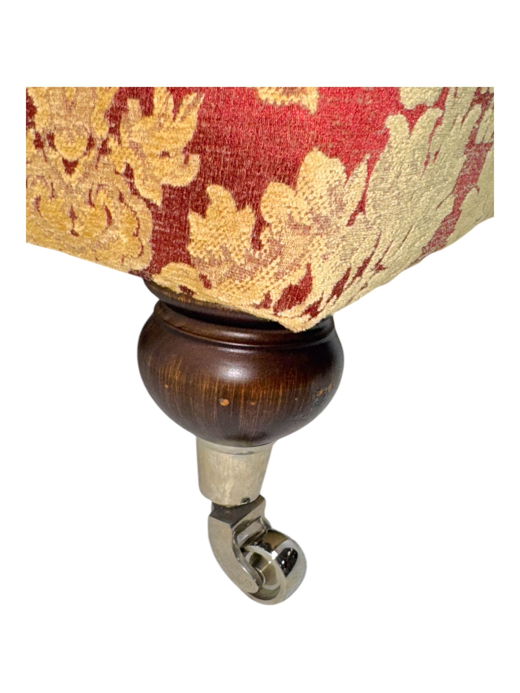 Duresta - pair of Grande three-seat sofas, traditional shaped with rolled arms and upholstered loose cushions, in red ground fabric with raised gold foliate pattern, on turned feet with brass castors 