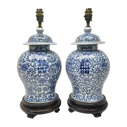 Pair of 20th century Chinese blue and white jars and covers, converted to table lamps, each of baluster form with domed cover, decorated with auspicious symbols, flower heads and training vines, upon turned circular wooden base, including fittings overall H43cm