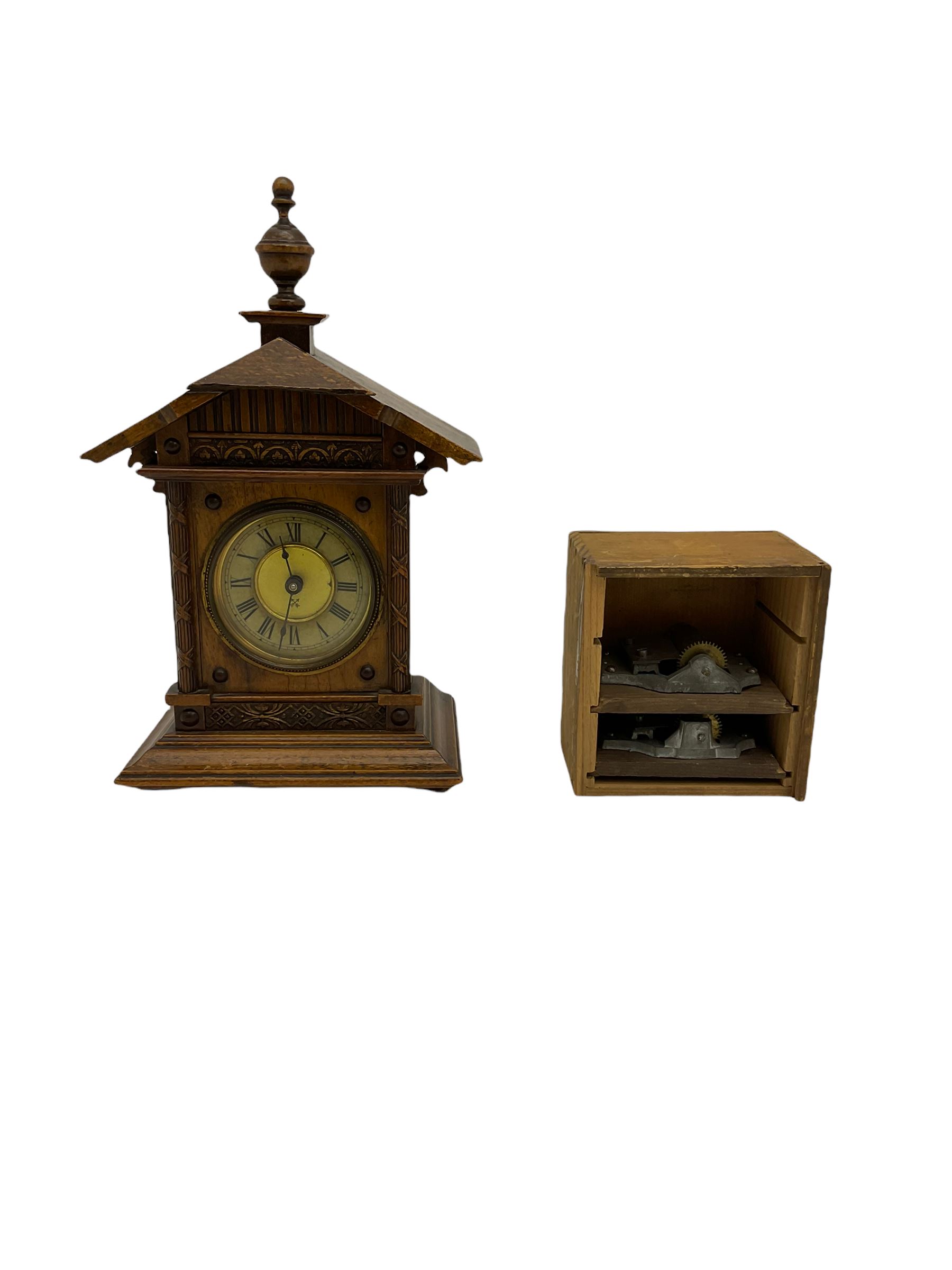A German musical alarm clock (model 1523/24) made by the Hamburg Amerikanische Uhrenfabrik c1880, in an oak case with an architectural top and finial, two-part dial with a gilt centre, ivorine chapter and steel spade hands, with roman numerals and minute track, case raised on four bun feet, with a thirty-hour balance wheel pin pallet spring driven movement sounding the alarm on a musical movement, key wound and set from the rear. Compete with three different and changeable musical movements in their original box. These clocks would have been sold as here with separate musical movements, it is rare to find them with the original clock.
H30 W17 D11 

	



