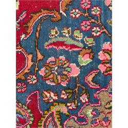 Pair of Persian wool rugs, each with rich red ground, one centred with a diamond-shaped medallion and navy spandrels within a floral field, the other with radiating floral medallion and scrolling foliate motifs, both enclosed by multiple borders with palmette and flowerhead designs, from the region of Kashan 291x376, 299 x 378 