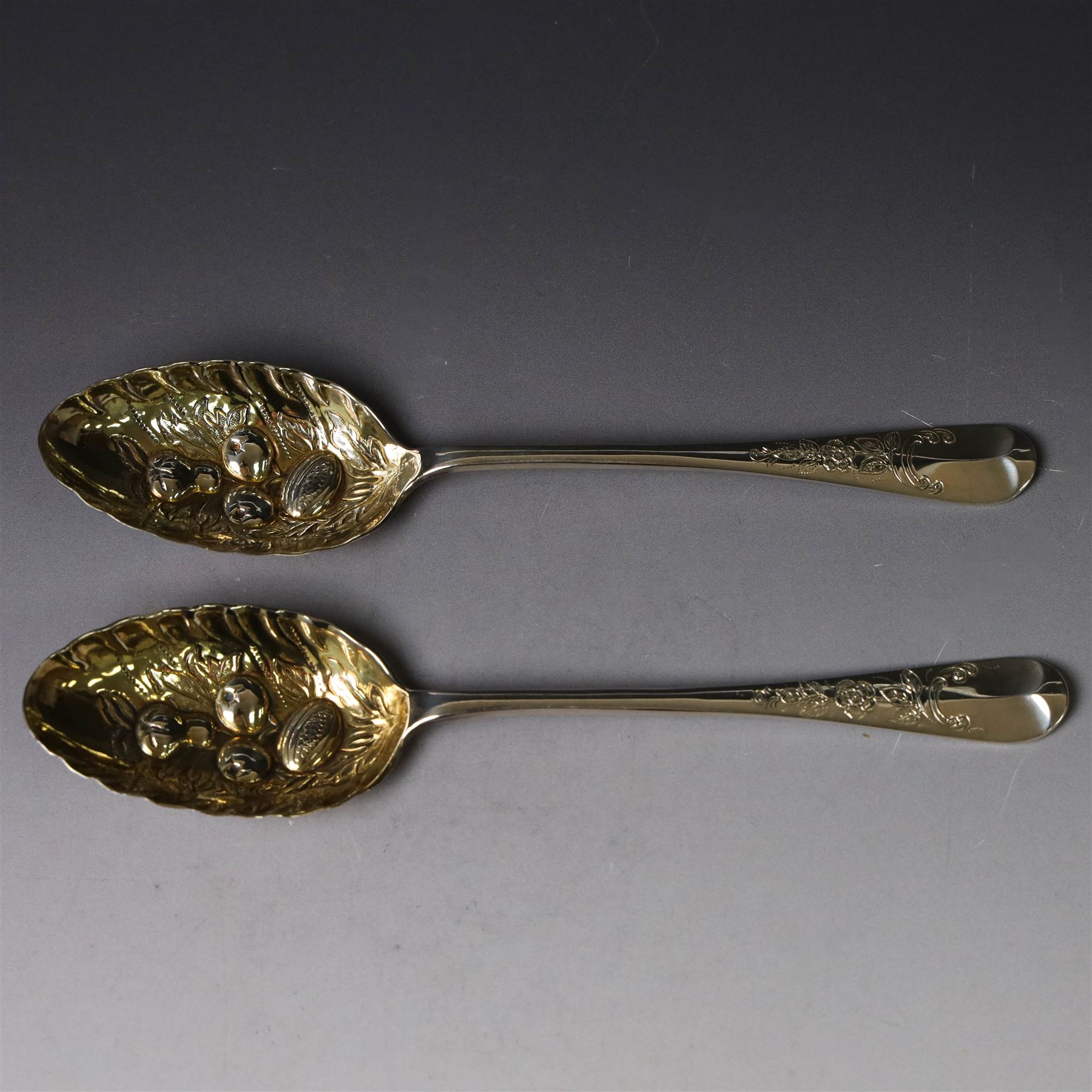 Mid 20th century silver berry spoons, each with gilt bowls embossed with fruit, with Queen Elizabeth II Coronation hallmark for C J Vander Ltd, London 1952, L22cmcm