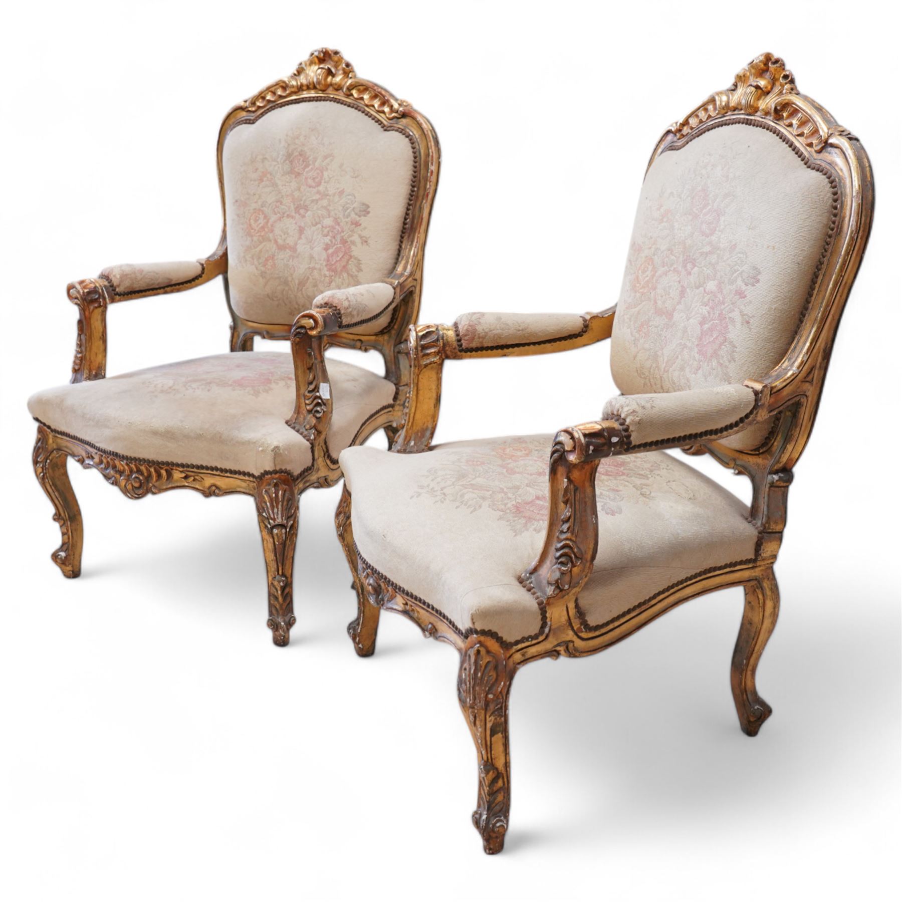 Pair of Louis XV design gilt framed armchairs, shaped cresting rail decorated with shells and foliage, upholstered in floral pattern fabric, on shell carved cabriole front supports 