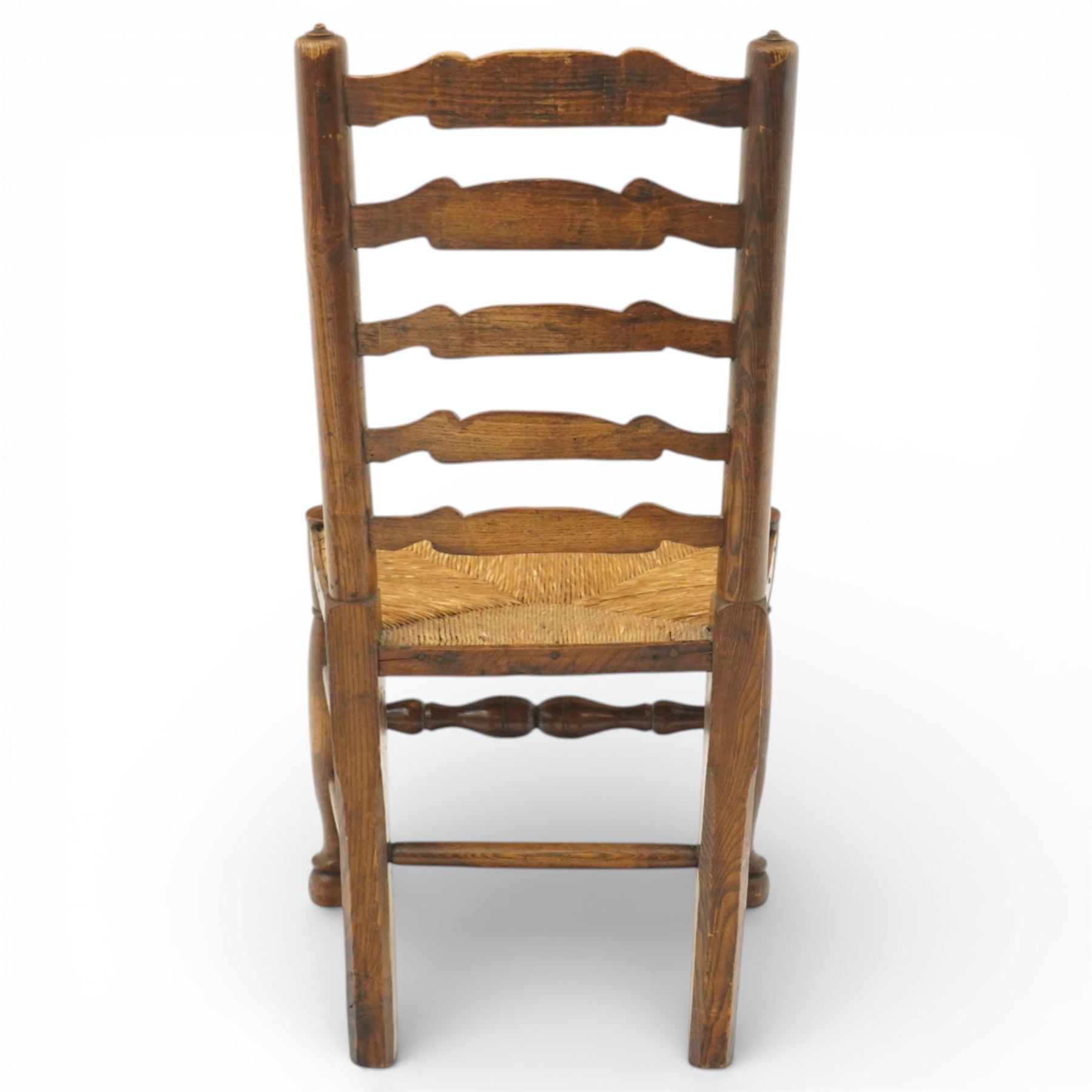 Early 19th century set of six country ladder back chairs, each with five shaped horizontal slats, woven rush seats within square frames, standing on turned forelegs united by peripheral stretchers with turned front rail